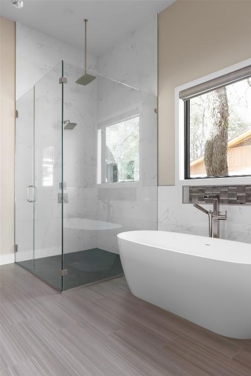 4704 Timberline Dr, Austin, TX 78746 - bathroom with a marble finish shower, wood finished floors, tile walls, and a soaking tub