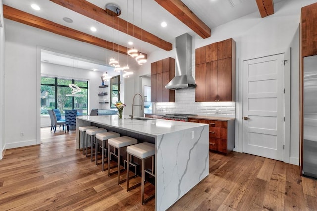 4704 Timberline Dr, Austin, TX 78746 - kitchen featuring wall chimney range hood, modern cabinets, brown cabinets, light wood finished floors, and beam ceiling