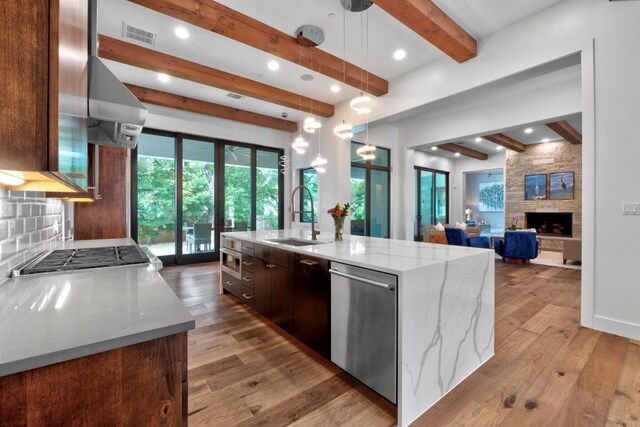 4704 Timberline Dr, Austin, TX 78746 - kitchen featuring a sink, beam ceiling, stainless steel appliances, light wood-type flooring, and an island with sink