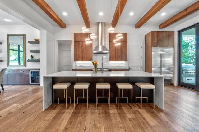 4704 Timberline Dr, Austin, TX 78746 - kitchen with stainless steel appliances, modern cabinets, wall chimney exhaust hood, wine cooler, and brown cabinets