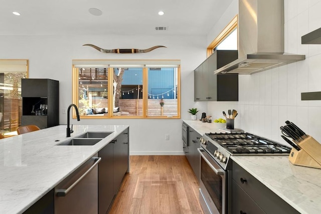 1411 Haskell St, Austin, TX 78702 - kitchen featuring range hood, appliances with stainless steel finishes, light wood-style flooring, light stone counters, and recessed lighting