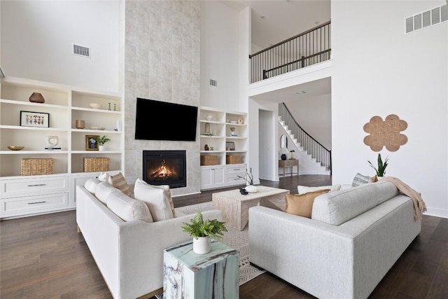 1005 Trevi Fontana, Leander, TX 78641 - living room featuring a high ceiling, stairs, a fireplace, dark wood finished floors, and built in features