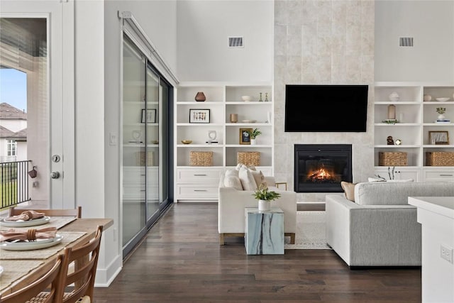 1005 Trevi Fontana, Leander, TX 78641 - living room featuring dark wood-style flooring, a tile fireplace, and built in shelves