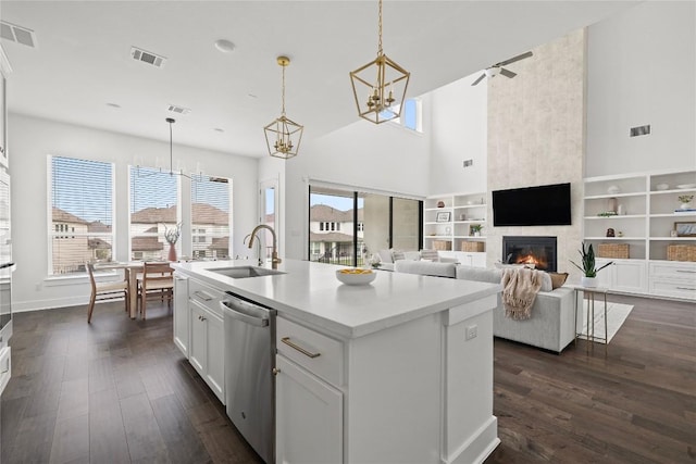 1005 Trevi Fontana, Leander, TX 78641 - kitchen with stainless steel dishwasher, a large fireplace, a chandelier, dark wood-style floors, and white cabinetry