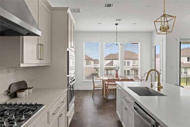 1005 Trevi Fontana, Leander, TX 78641 - kitchen with extractor fan, appliances with stainless steel finishes, a chandelier, decorative backsplash, and hanging light fixtures