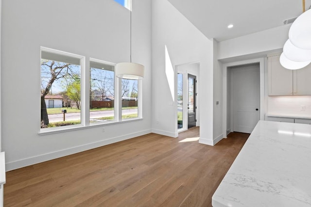 710 Philco Dr, Austin, TX 78745 - unfurnished living room featuring healthy amount of natural light, wood finished floors, baseboards, a towering ceiling, and recessed lighting