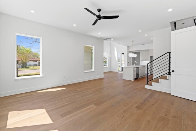 710 Philco Dr, Austin, TX 78745 - unfurnished living room featuring light wood-type flooring, recessed lighting, stairs, a sink, and baseboards