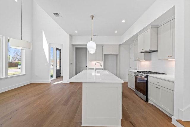 710 Philco Dr, Austin, TX 78745 - kitchen featuring visible vents, stainless steel range with gas stovetop, a sink, light wood-style floors, and backsplash
