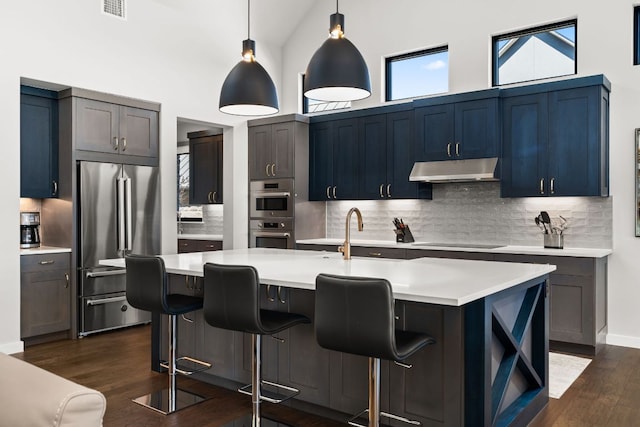 316 Hidden Beacon Bnd, Lakeway, TX 78738 - kitchen featuring stainless steel appliances, under cabinet range hood, dark wood-style floors, light countertops, and backsplash