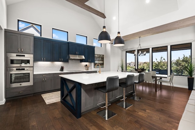 316 Hidden Beacon Bnd, Lakeway, TX 78738 - kitchen with under cabinet range hood, light countertops, cooktop, high vaulted ceiling, and dark wood-style flooring