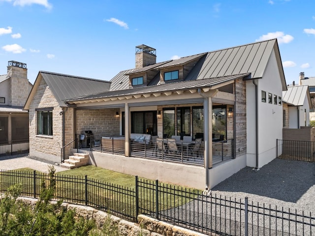 316 Hidden Beacon Bnd, Lakeway, TX 78738 - rear view of house featuring a standing seam roof, metal roof, stone siding, a chimney, and a sunroom