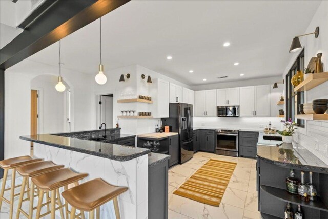 1905 Big Horn Dr, Austin, TX 78734 - kitchen featuring open shelves, appliances with stainless steel finishes, dark stone countertops, arched walkways, and decorative backsplash