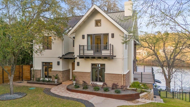 1905 Big Horn Dr, Austin, TX 78734 - view of front of property featuring a balcony, stucco siding, a standing seam roof, a chimney, and metal roof