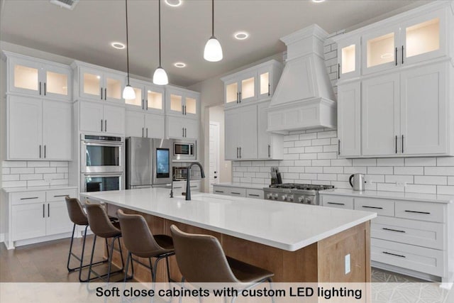 145 Gaston Dr, Bastrop, TX 78602 - kitchen featuring custom exhaust hood, appliances with stainless steel finishes, a sink, a center island with sink, and backsplash
