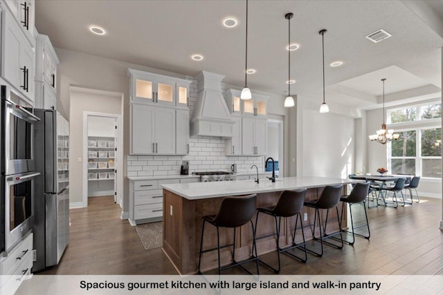 145 Gaston Dr, Bastrop, TX 78602 - kitchen with an inviting chandelier, premium range hood, baseboards, dark wood-style flooring, and visible vents