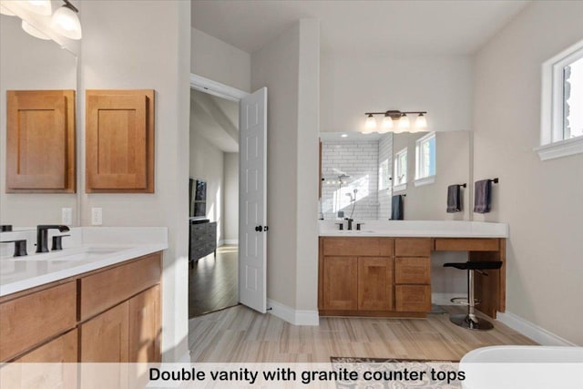 145 Gaston Dr, Bastrop, TX 78602 - full bath featuring a sink, two vanities, wood finished floors, and baseboards