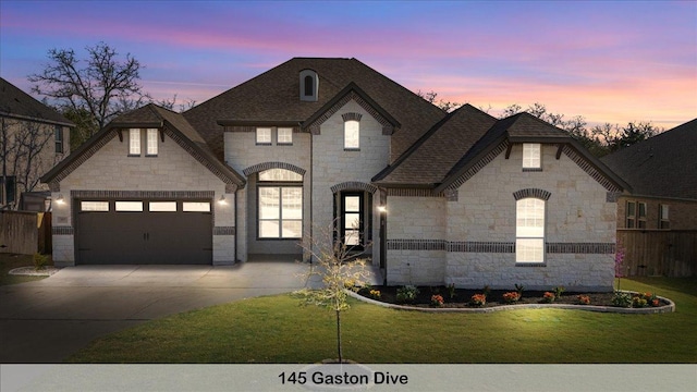145 Gaston Dr, Bastrop, TX 78602 - view of front of home with a front lawn, driveway, stone siding, an attached garage, and fence