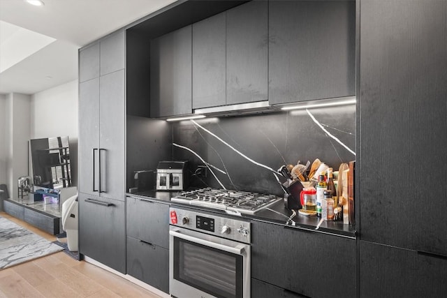 44 E Ave Unit 3402, Austin, TX 78701 - kitchen with stainless steel appliances, light wood-type flooring, tasteful backsplash, dark countertops, and gray cabinets