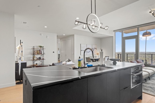 44 E Ave Unit 3402, Austin, TX 78701 - kitchen featuring a large island with sink, a sink, open floor plan, light wood-style flooring, and stainless steel oven