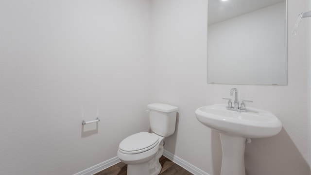 bathroom featuring baseboards, wood finished floors, and toilet