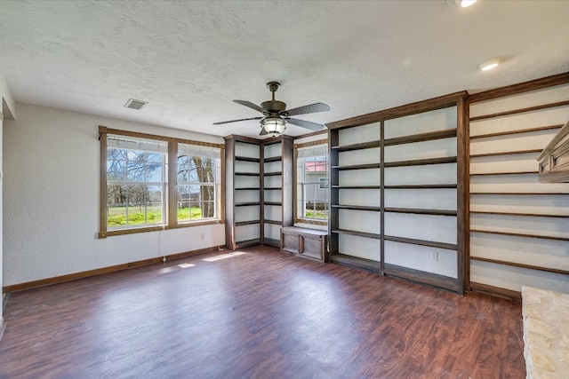 empty room featuring dark wood-type flooring, baseboards, a textured ceiling, and a ceiling fan
