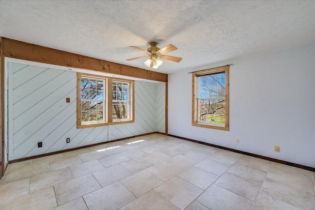 spare room with baseboards, healthy amount of natural light, ceiling fan, and a textured ceiling