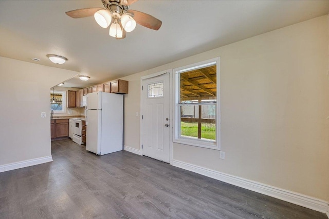 kitchen with white appliances, dark wood-style flooring, ceiling fan, and baseboards