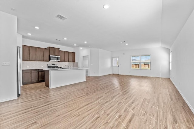 130 Carmello, Kyle, TX 78640 - kitchen featuring appliances with stainless steel finishes, open floor plan, recessed lighting, light wood-style flooring, and tasteful backsplash
