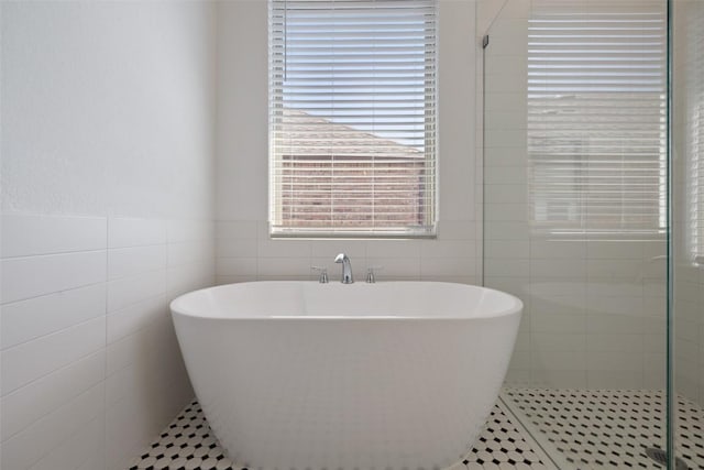 full bathroom featuring tile walls, a freestanding tub, and a stall shower