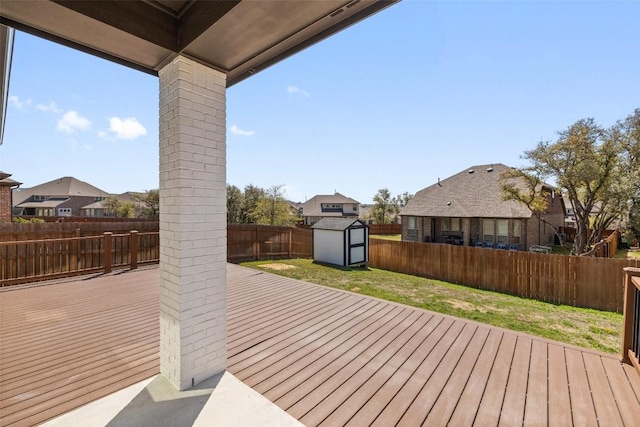 deck with a fenced backyard, an outdoor structure, a yard, and a shed