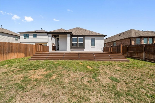 rear view of house featuring a fenced backyard, a wooden deck, brick siding, and a yard