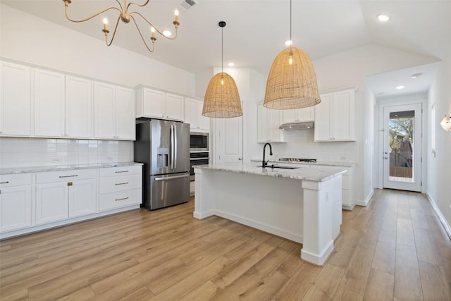 kitchen featuring a sink, appliances with stainless steel finishes, lofted ceiling, and light wood finished floors