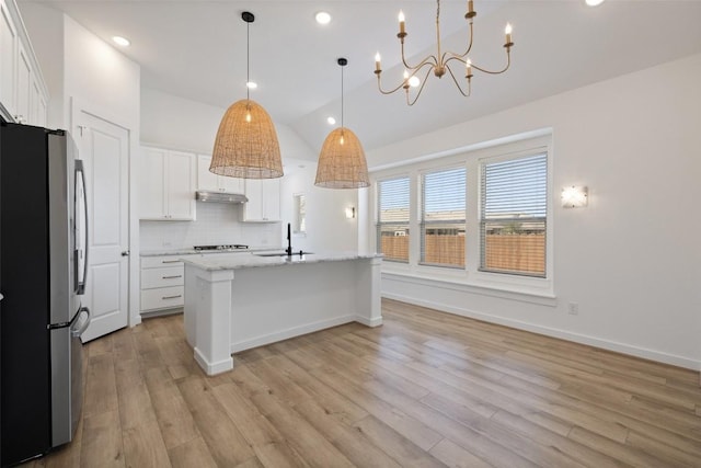 kitchen with white cabinets, decorative backsplash, a sink, freestanding refrigerator, and light wood-style flooring