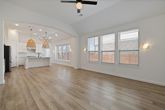 unfurnished living room with lofted ceiling, baseboards, light wood finished floors, visible vents, and a ceiling fan