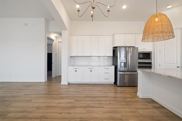 kitchen featuring light stone countertops, appliances with stainless steel finishes, light wood-style flooring, white cabinets, and decorative backsplash