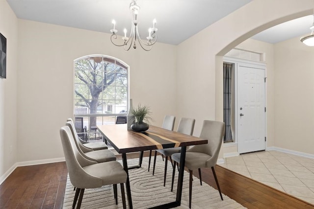 2701 Blackstone Cv, Round Rock, TX 78665 - dining space featuring arched walkways, light wood finished floors, a chandelier, and baseboards