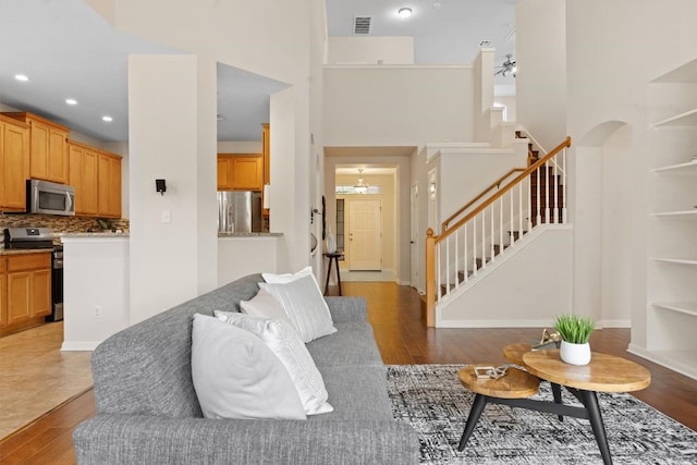 2701 Blackstone Cv, Round Rock, TX 78665 - living room with stairs, light wood-style flooring, a towering ceiling, recessed lighting, and built in shelves
