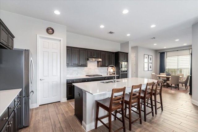 9003 Jodie Ln, Austin, TX 78748 - kitchen with appliances with stainless steel finishes, a sink, light wood finished floors, decorative backsplash, and light countertops