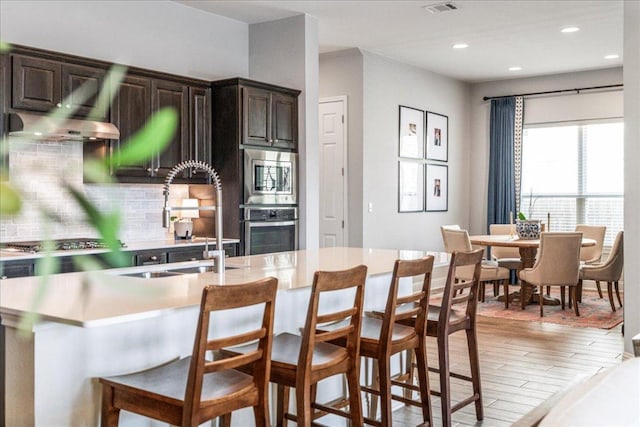 9003 Jodie Ln, Austin, TX 78748 - kitchen featuring appliances with stainless steel finishes, a sink, light countertops, a kitchen breakfast bar, and tasteful backsplash