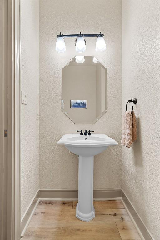 bathroom with wood finished floors, baseboards, and a textured wall