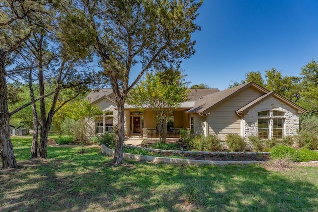 view of front of home with stone siding, a front yard, and covered porch