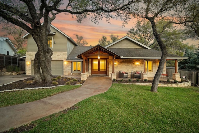 7603 Rustling Cv, Austin, TX 78731 - view of front of house with stone siding, an attached garage, driveway, an outdoor hangout area, and a shingled roof