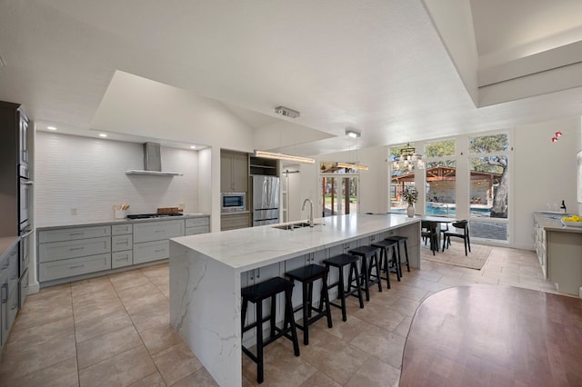 7603 Rustling Cv, Austin, TX 78731 - kitchen with appliances with stainless steel finishes, wall chimney exhaust hood, a spacious island, light stone counters, and a breakfast bar