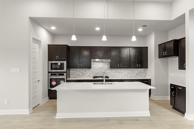600 C-Bar Ranch Trl Unit 116, Cedar Park, TX 78613 - kitchen featuring appliances with stainless steel finishes, under cabinet range hood, tasteful backsplash, light countertops, and light wood-style flooring