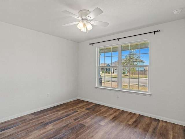 empty room featuring ceiling fan, baseboards, and dark wood finished floors
