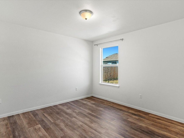 empty room featuring baseboards and dark wood finished floors