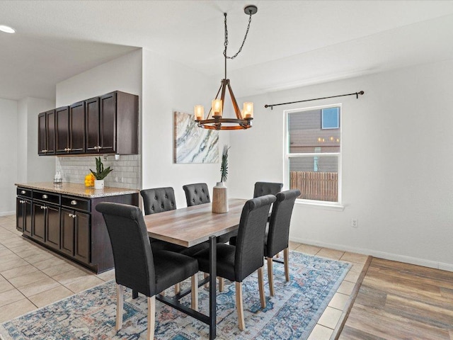 dining space featuring light tile patterned floors, a notable chandelier, and baseboards