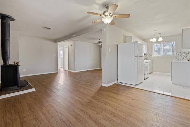 703 S 13th St, Copperas Cove, TX 76522 - unfurnished living room with a wood stove, a ceiling fan, light wood-style flooring, and a chandelier