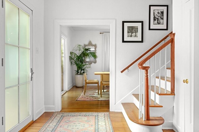 foyer with baseboards, stairs, and light wood finished floors