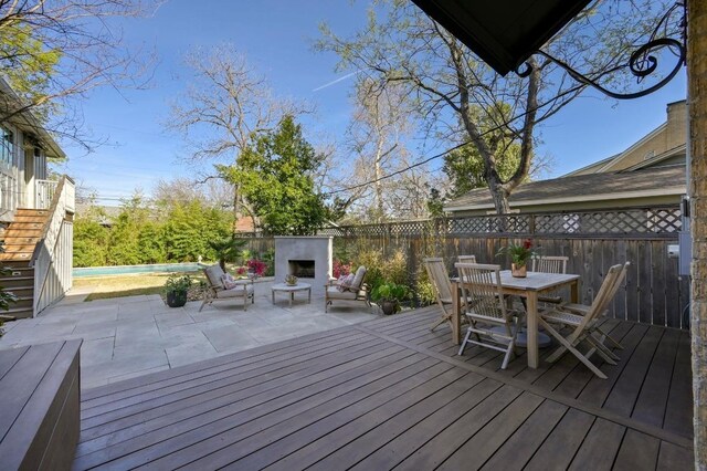 deck featuring a pool, an outdoor fireplace, outdoor dining space, a fenced backyard, and a patio